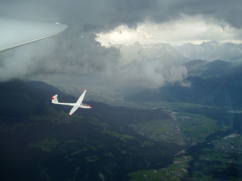 Segelflugzeug über dem Tal, im Hintergrund die Alpen